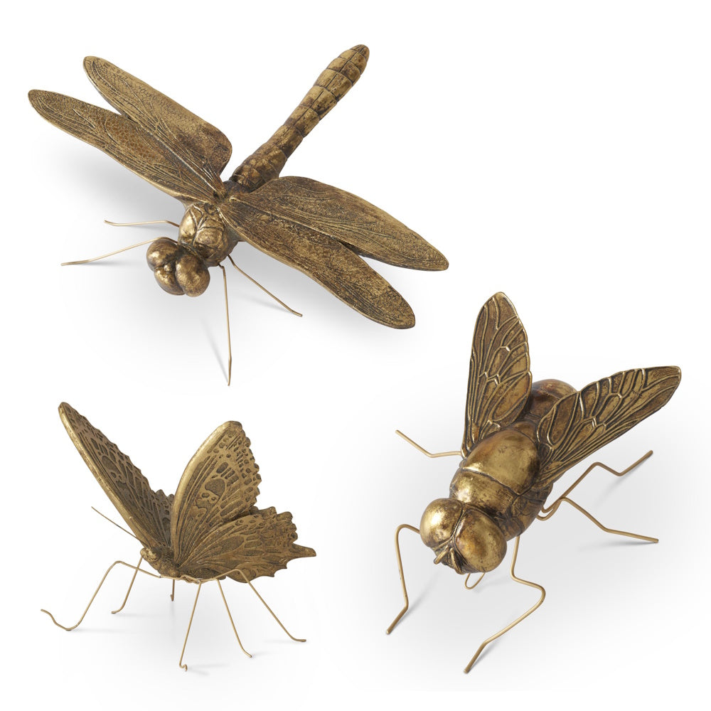 Three gold resin insect figurines including a dragonfly, butterfly, and fly with wire legs on a white background.