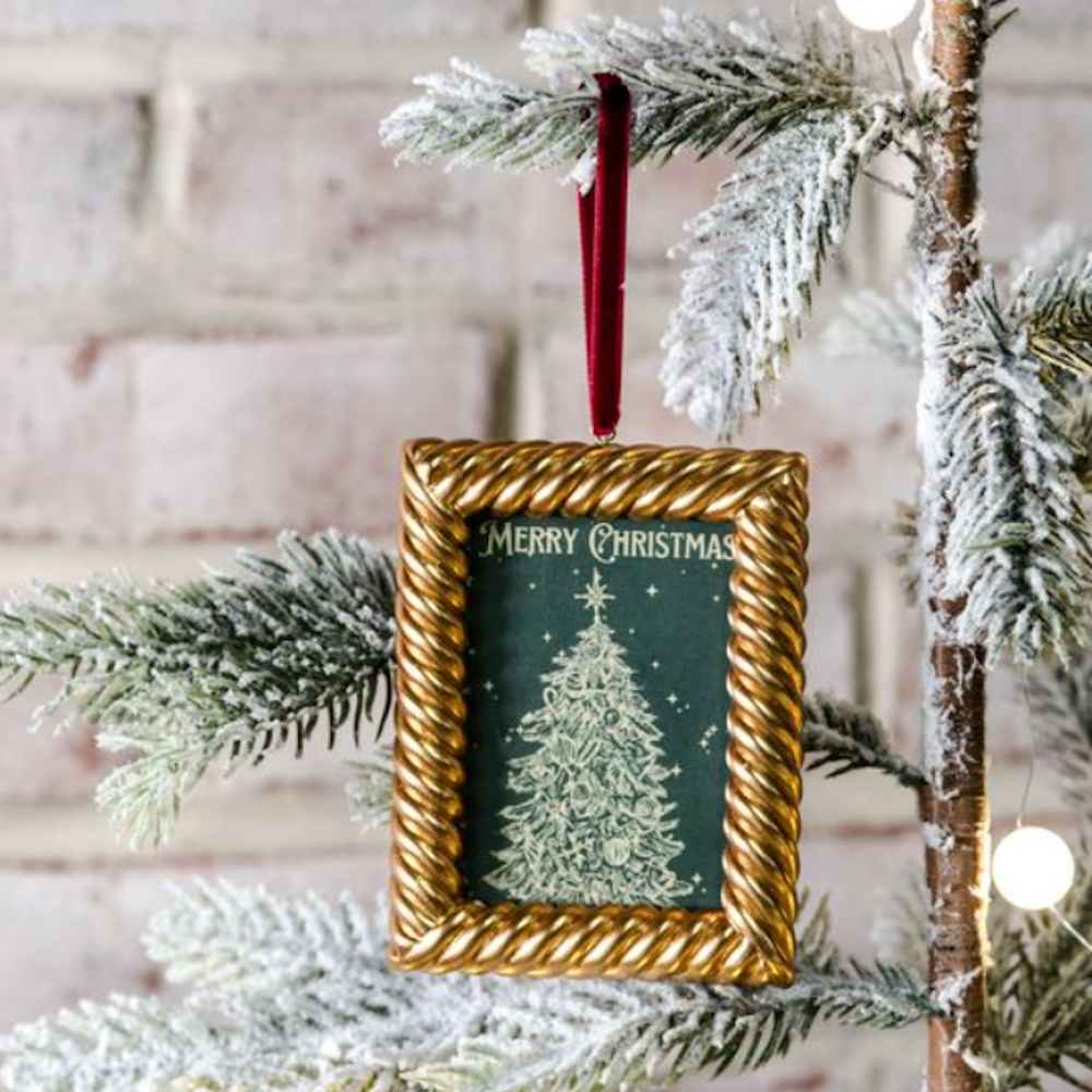 Rectangular gold twisted-frame ornament featuring a "Merry Christmas" tree print hanging on a tree.