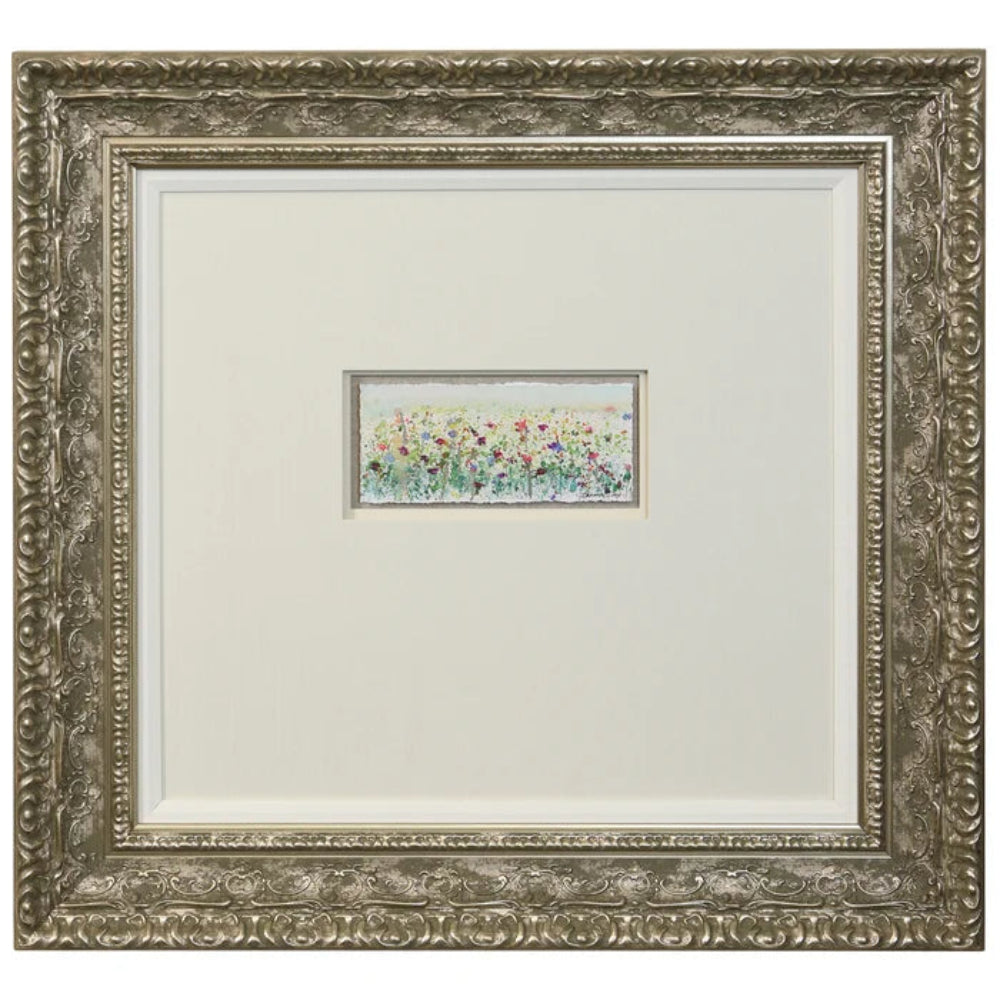 Ornate silver-framed wall art featuring a small, colorful wildflower meadow watercolor painting on white matting.