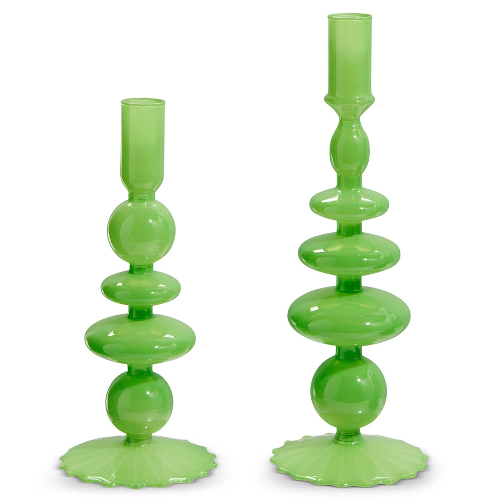 Two modern, green glass candlestick holders with a glossy finish. The taller one has a more intricate design, both have a layered, geometric silhouette.