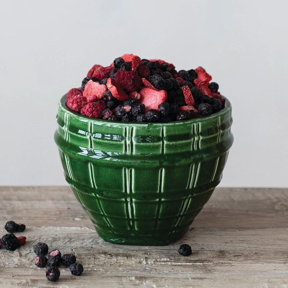 Green debossed stoneware planter filled with dried berries and strawberries on a rustic wooden table.