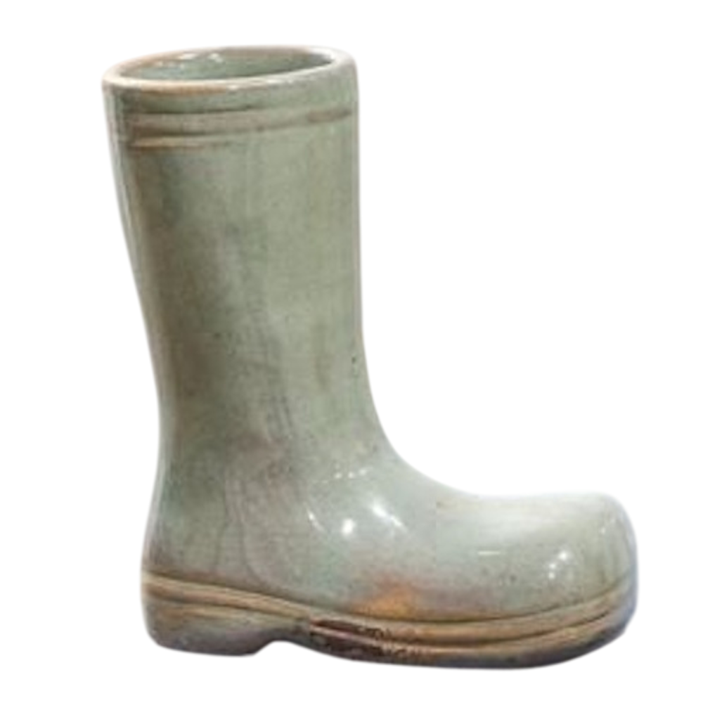 A small, light green ceramic planter shaped like a glossy rain boot with a brown rimmed sole.