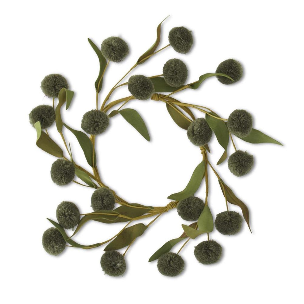 A minimal wreath made of green yarn pom-poms and artificial leaves on a plain white background.