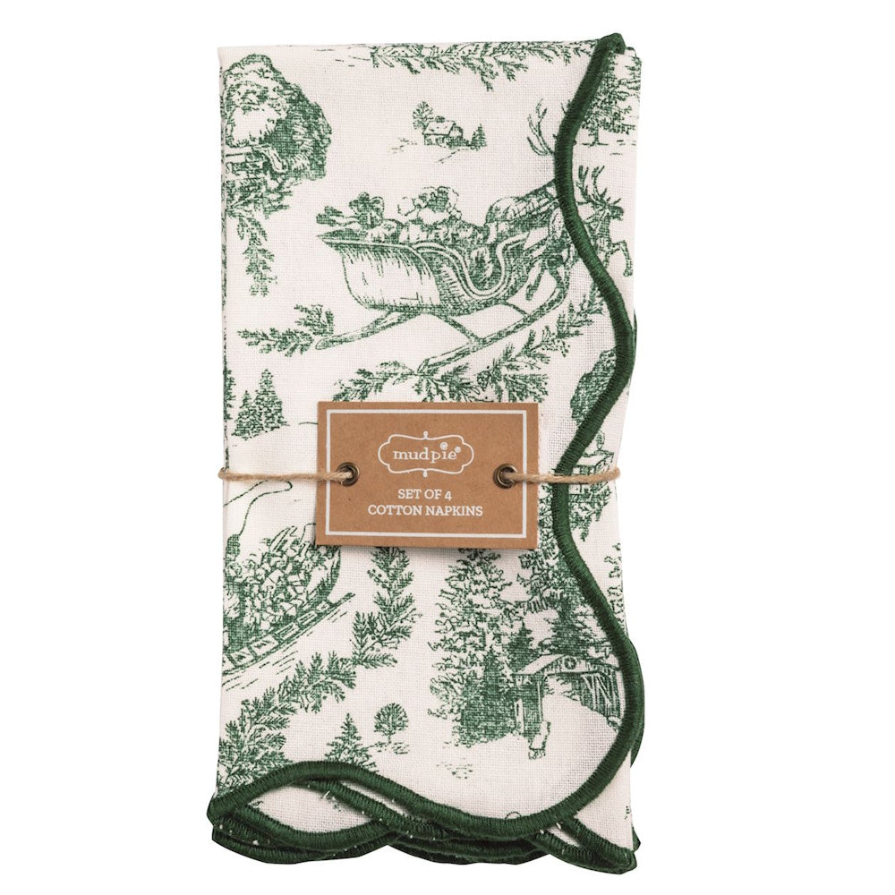 Set of four folded cotton napkins with green holiday toile print and dark green scalloped edges.