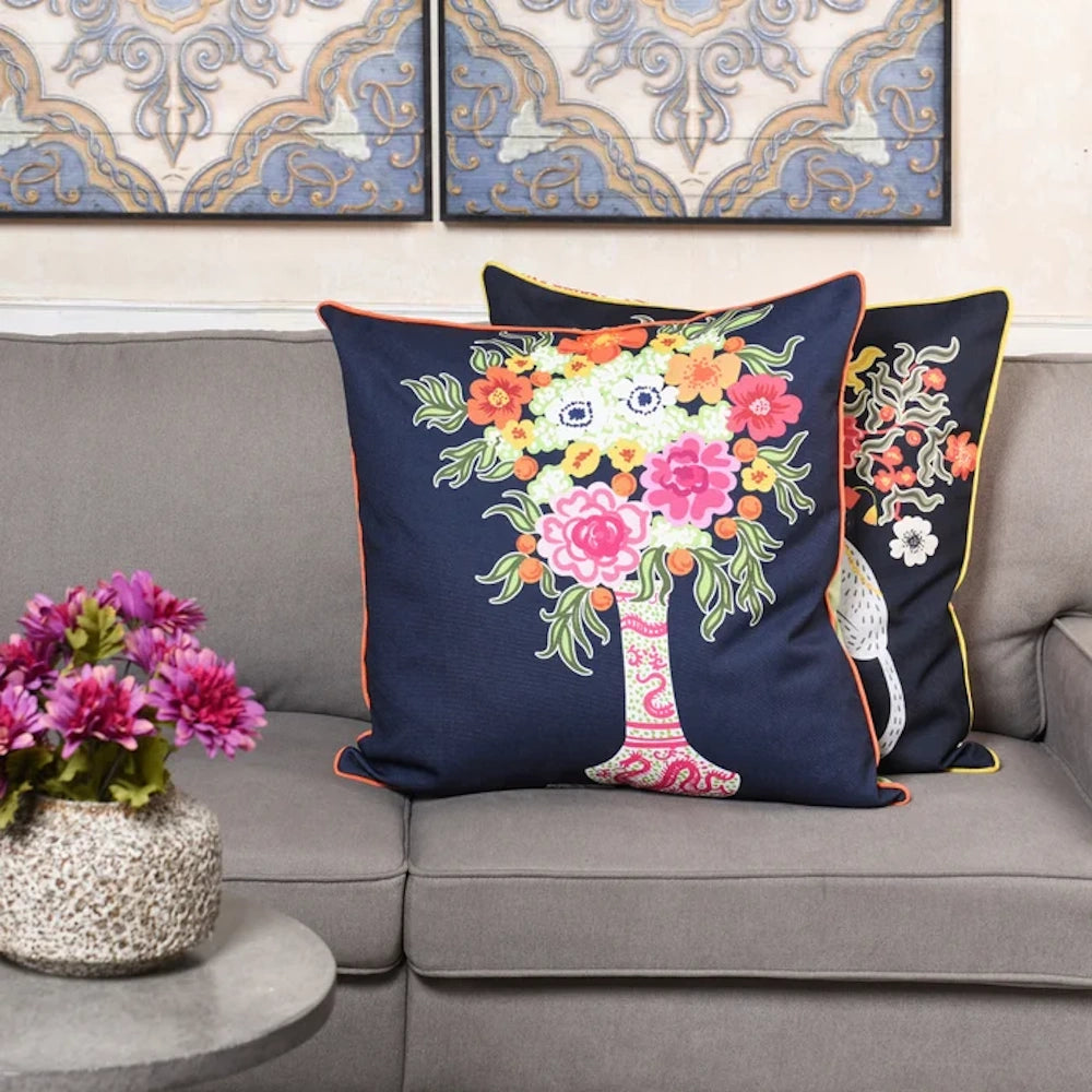 Navy blue throw pillows with colorful floral bouquet embroidery on a grey sofa for modern living room decor.