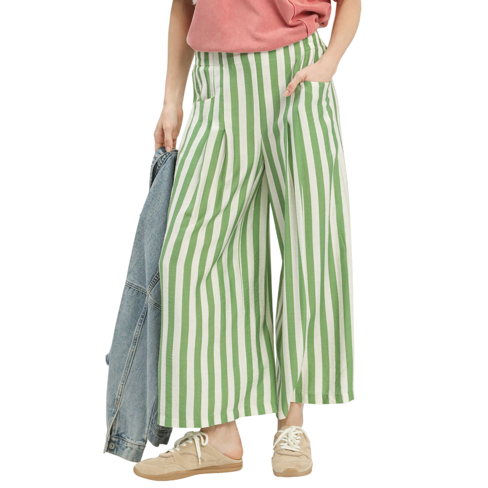 A person wearing wide-leg pants with green and white vertical stripes, paired with tan sneakers.