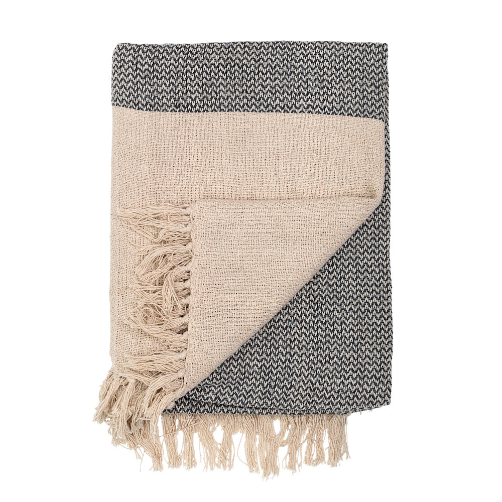 Folded grey textured knit throw blanket with a contrasting cream-colored underside and a fringed edge.