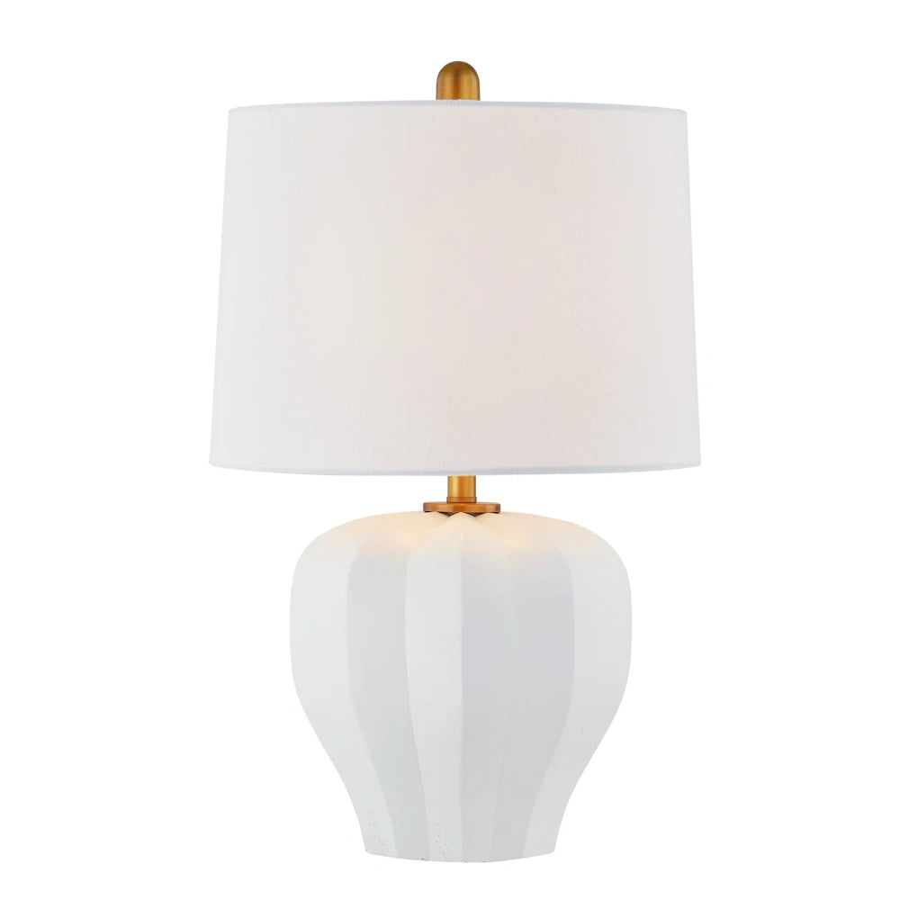 White ceramic table lamp with sculpted geometric base, white drum shade and brushed brass accents.