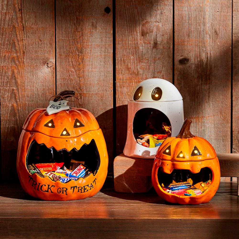 Three light-up ceramic Halloween candy dishes shaped like jack-o'-lanterns and a ghost.