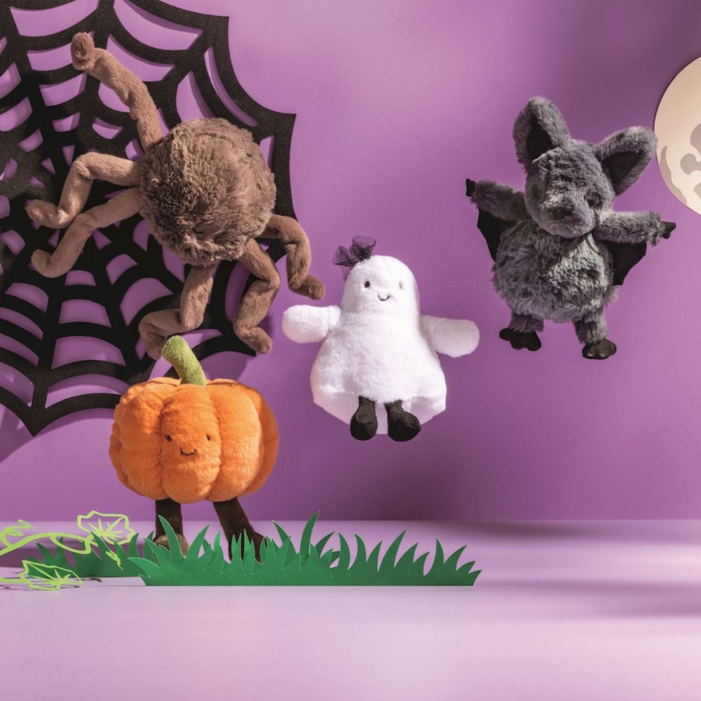 Four Halloween plush toys including a spider, pumpkin, ghost, and bat against a purple background.