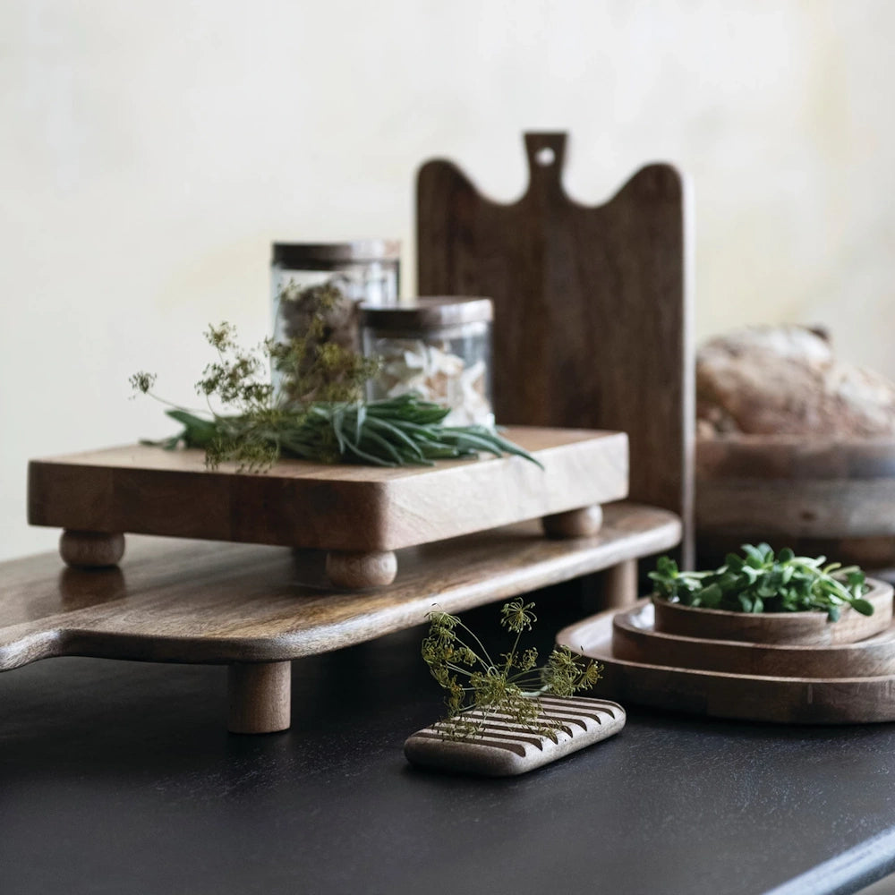 Hand-blown glass jars with mango wood lids on tiered wooden pedestals, rustic kitchen storage and decor styling.