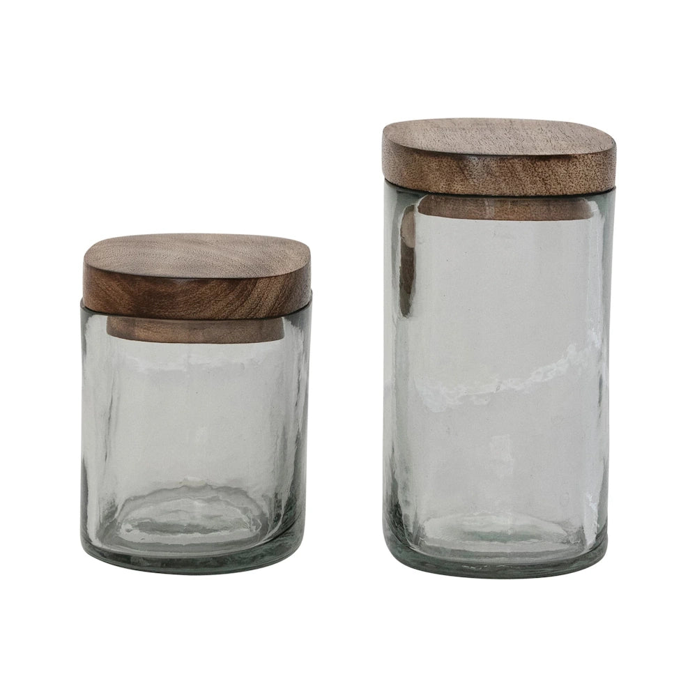 Two hand-blown clear glass jars with mango wood lids, eco-friendly kitchen storage containers on white background.