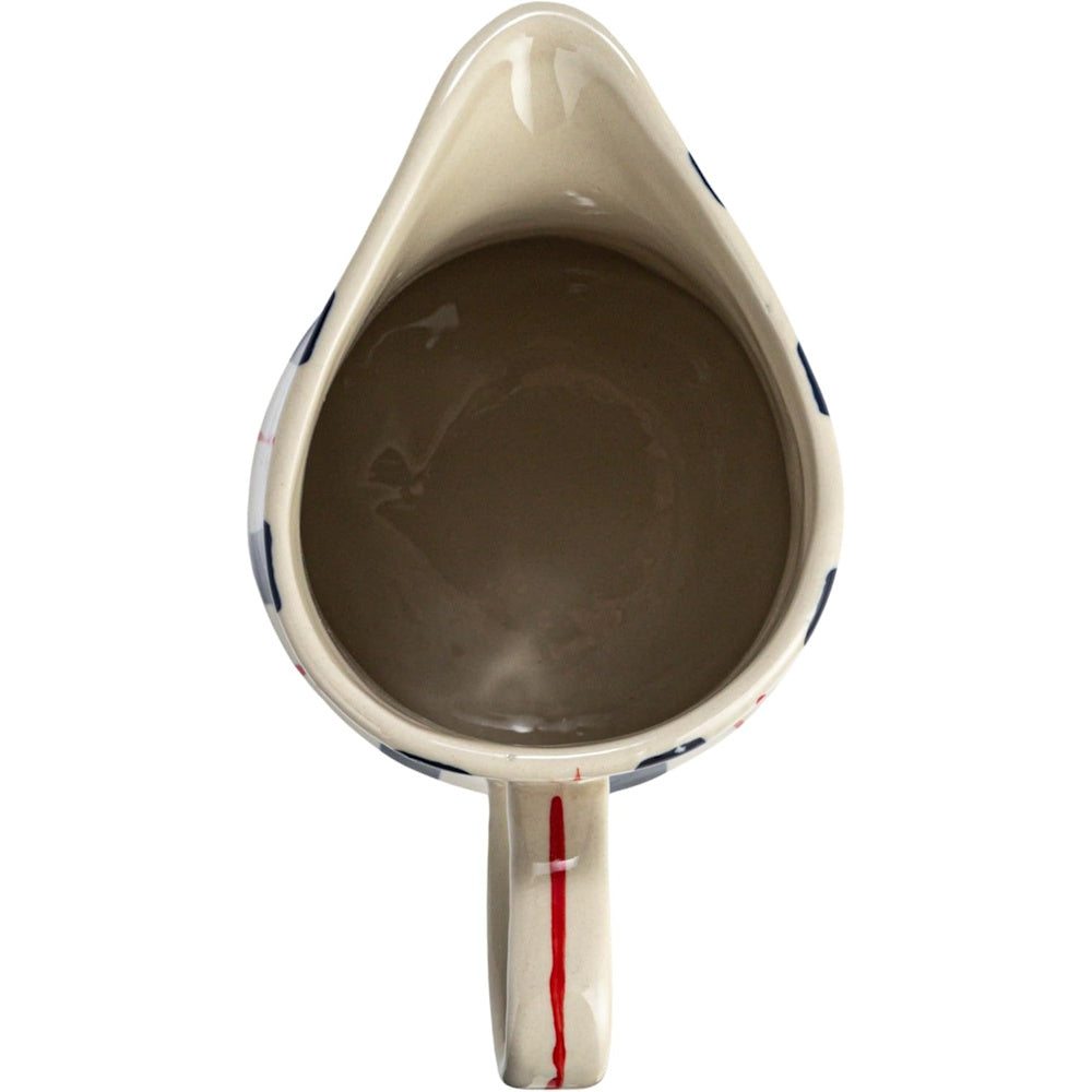 Top-down view of an off-white ceramic pitcher with blue stripes and a single red stripe painted on the handle.