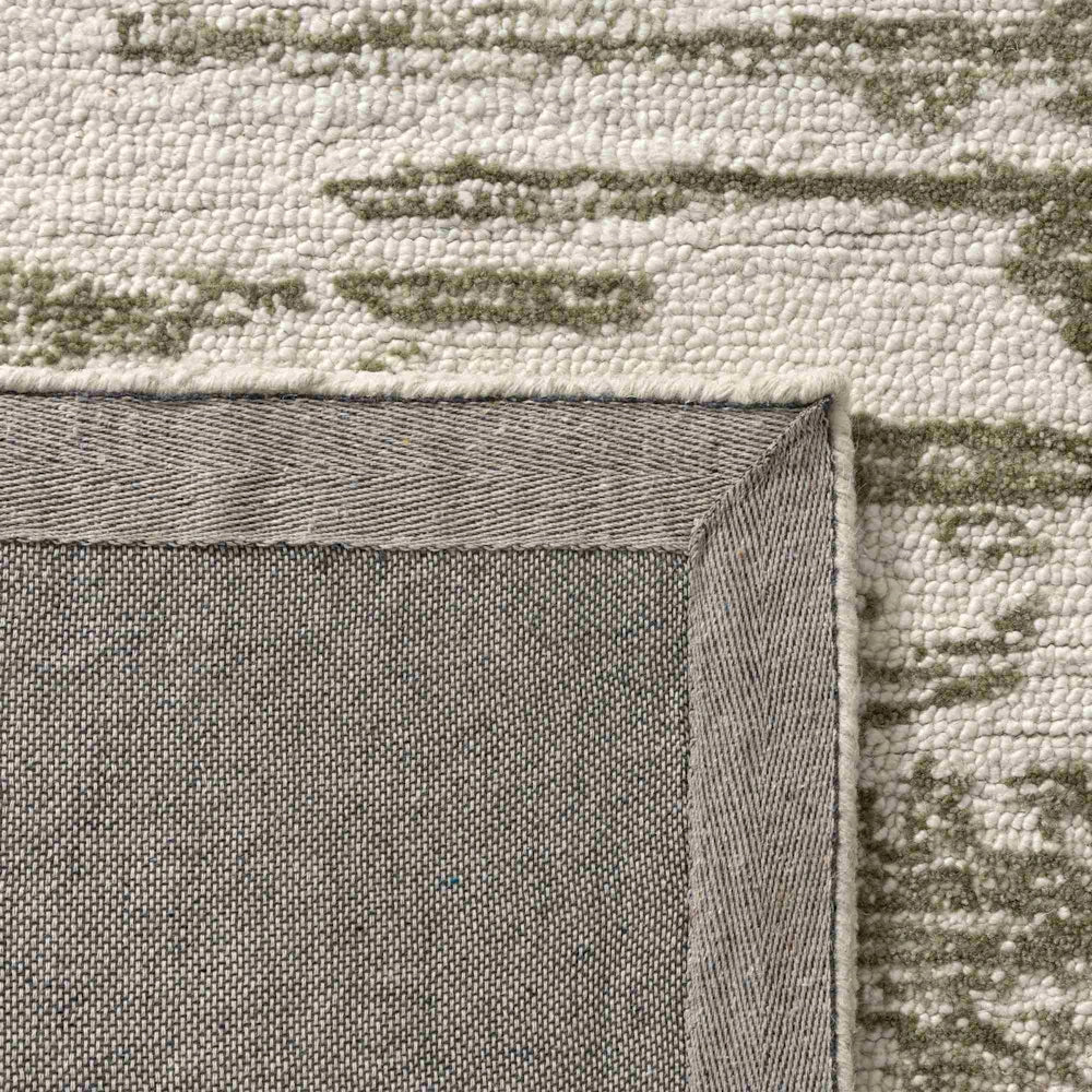 Close up of green and ivory hand tufted rug backing showing durable woven underside and bound edge finish.