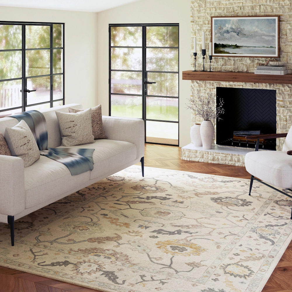 Modern living room with a cream patterned area rug, white sofa, and stone fireplace.