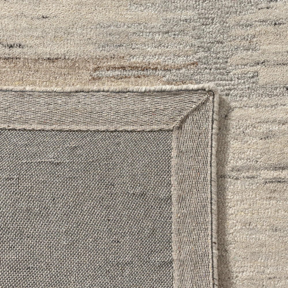 Close up of cream hand tufted rug backing showing durable woven underside and bound edge finish.