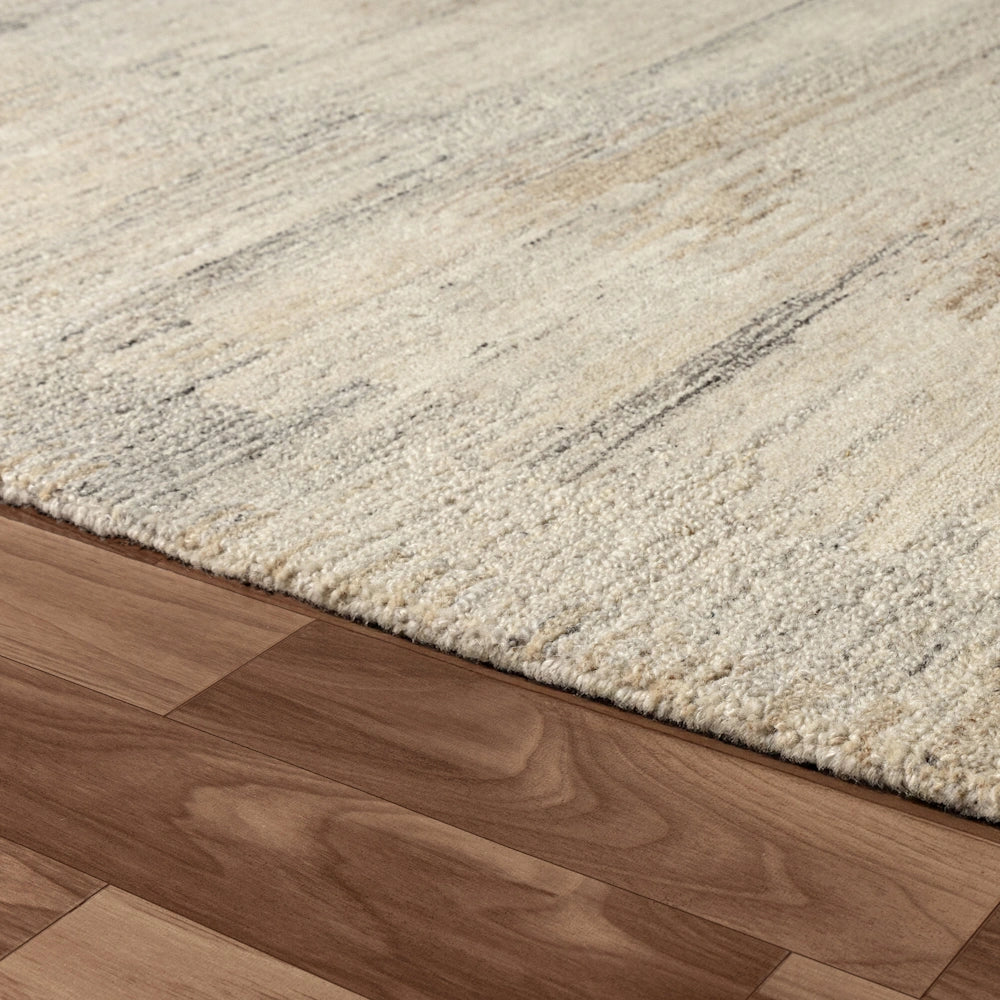Close up of cream hand tufted rug edge with subtle striated pattern, textured pile and soft neutral finish.