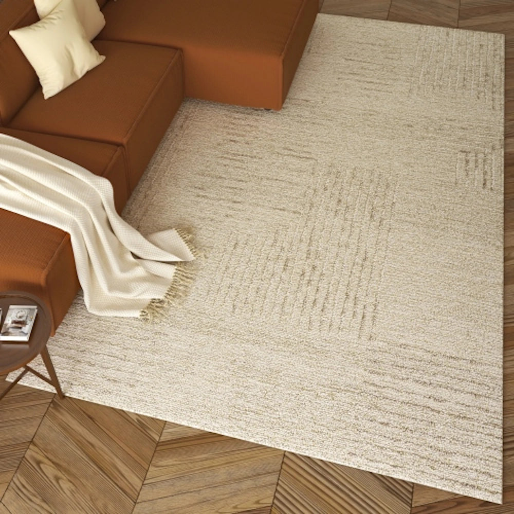 Oatmeal hand tufted rectangle haze rug in a living room next to a brown sectional sofa.