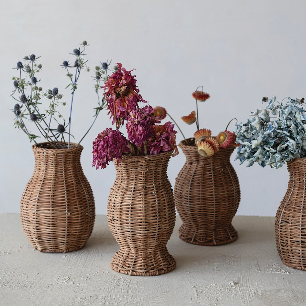 Hand-woven natural rattan vases arranged with dried floral stems in a rustic interior decor setting.