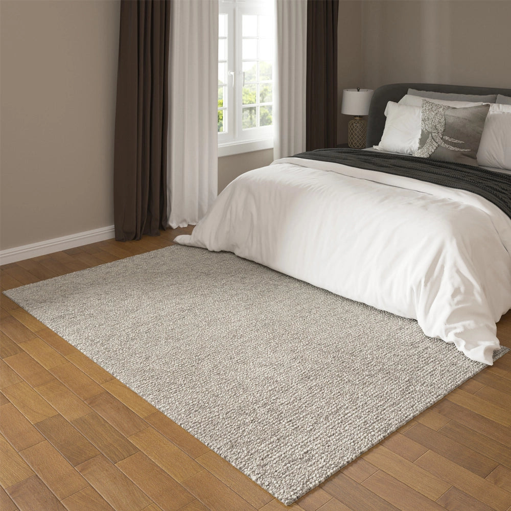 Hand-woven rectangle dome rug under a bed in a bedroom.