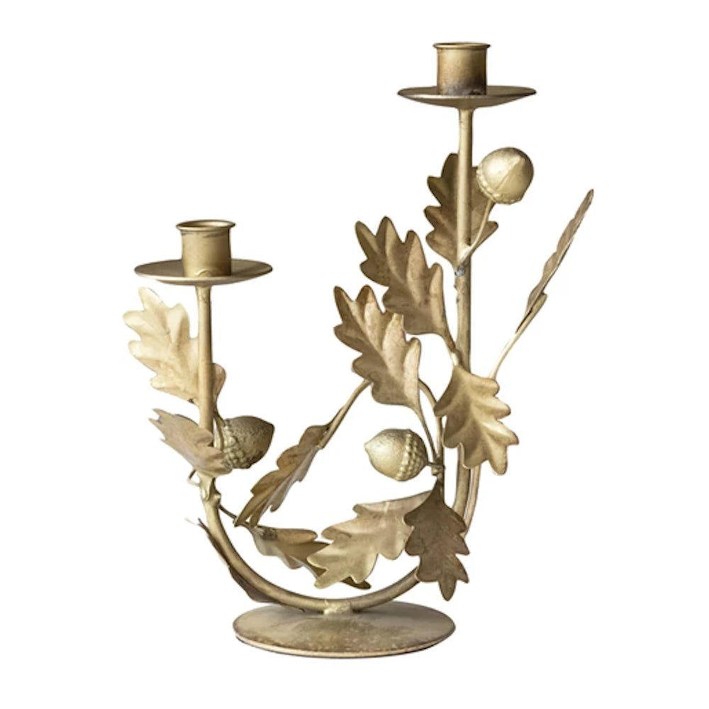 Gold-toned metal candelabra featuring a decorative oak leaves and acorns design on a white background.