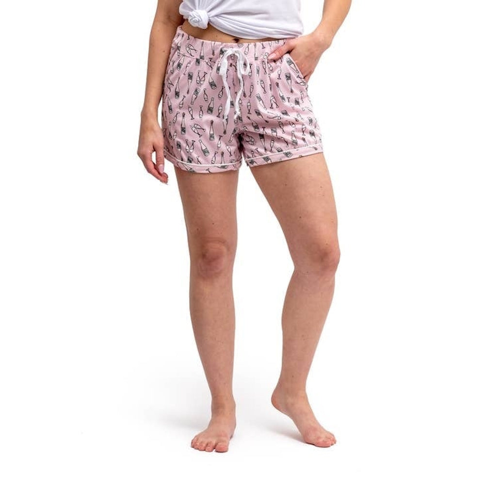 A person wearing pink pajama shorts with a white drawstring and a pattern of champagne bottles.