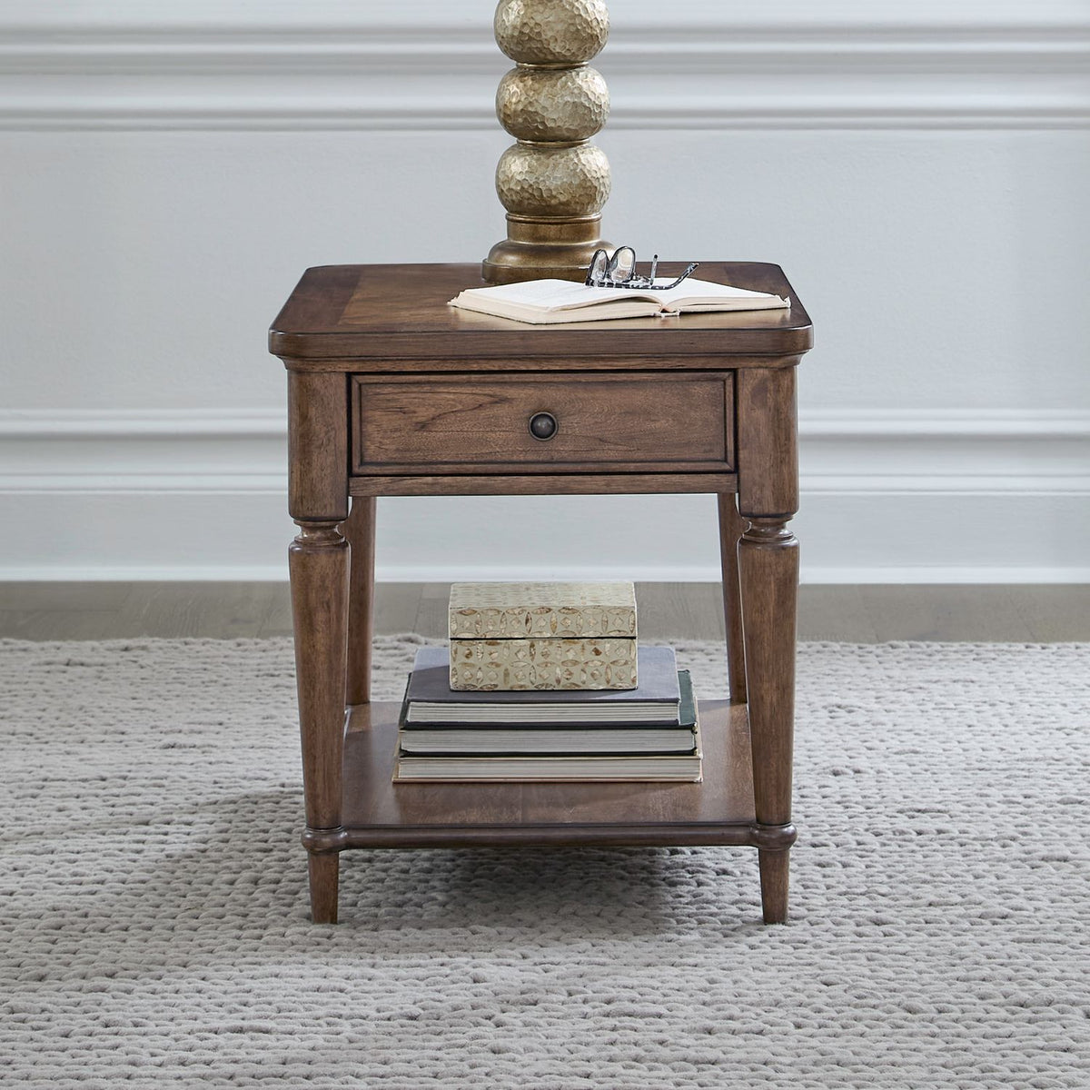 Harrison Heights wooden end table with drawer, bottom shelf, lamp, and books on a gray textured rug.