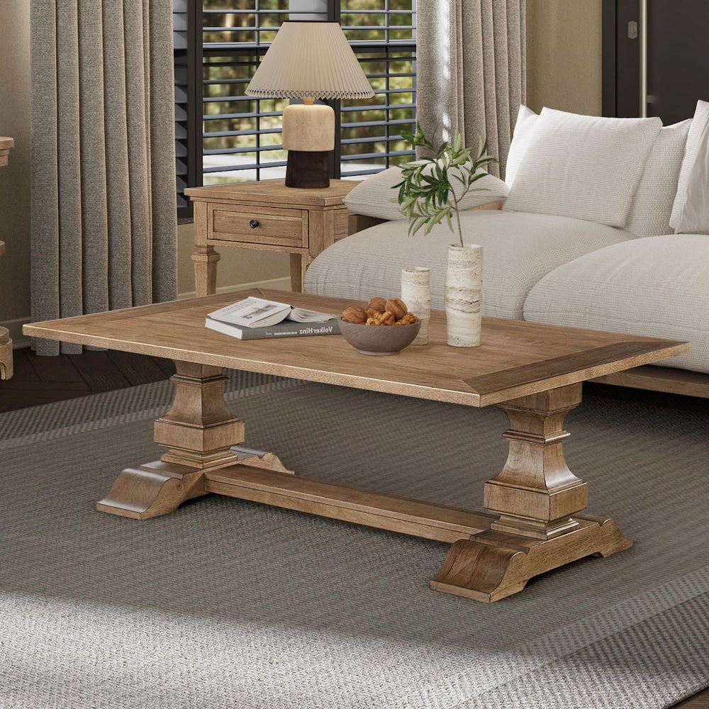 Rectangular wood cocktail table with pedestal base styled in a cozy living room setting.