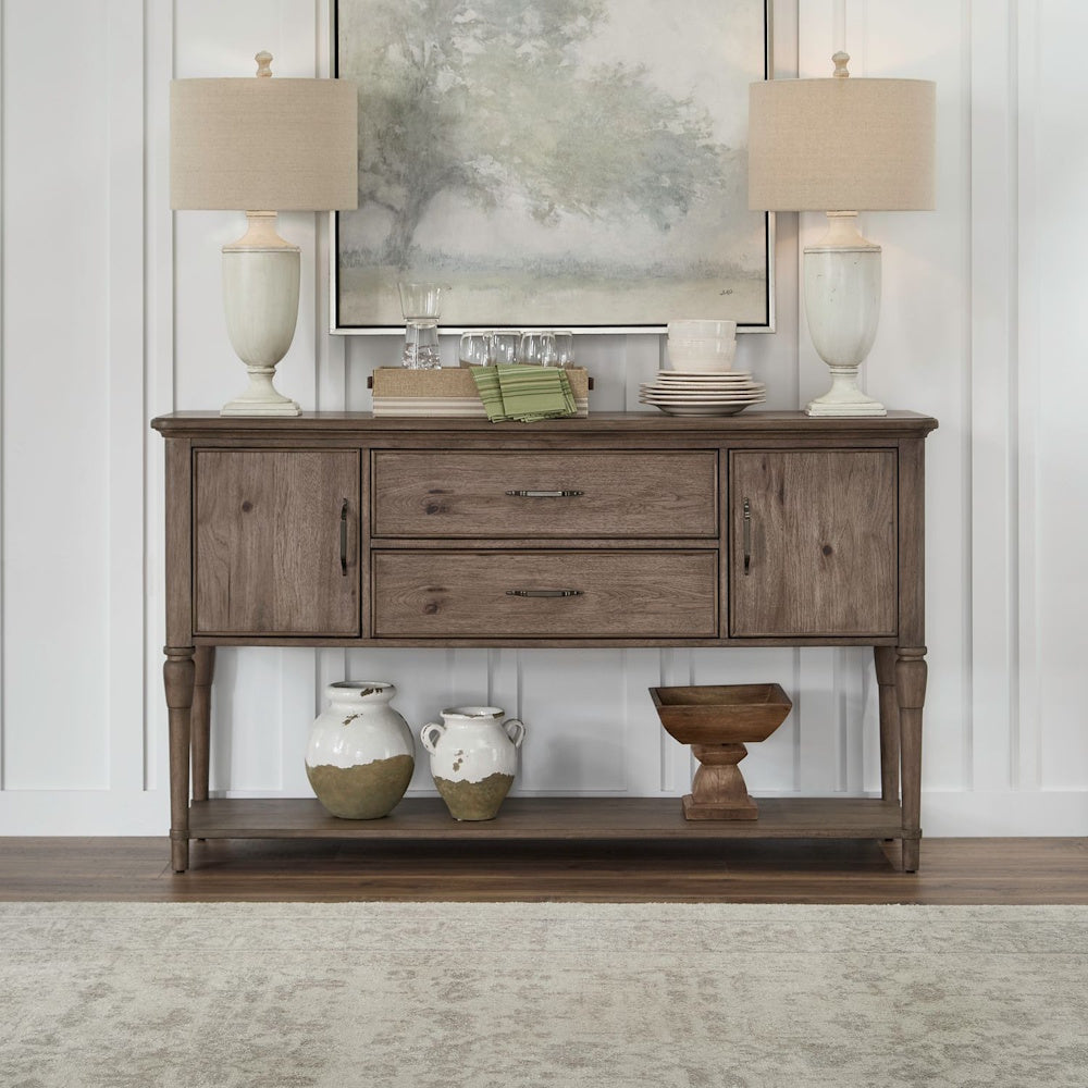 Rustic wood sideboard buffet table styled with two lamps, dishware, and decorative ceramic vases below.