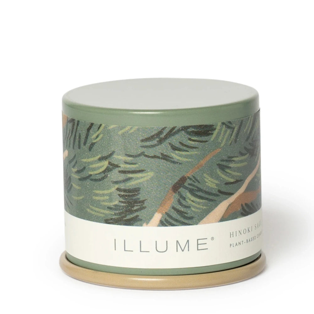 Closed Illume candle tin with a green pine tree pattern and Hinoki Sage label on a white background.