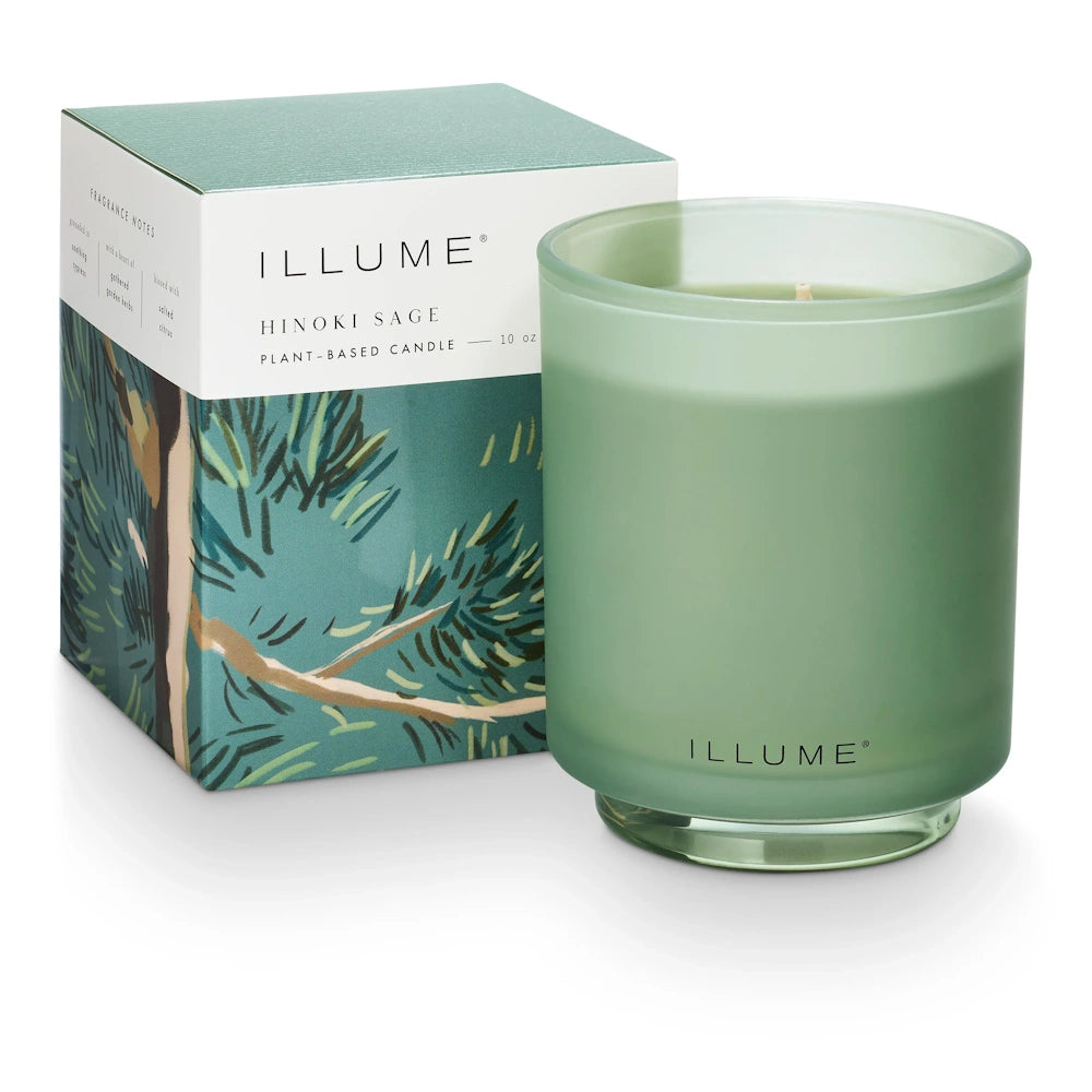 Illume Hinoki Sage scented plant-based candle in a frosted green glass jar next to its botanical-print box.