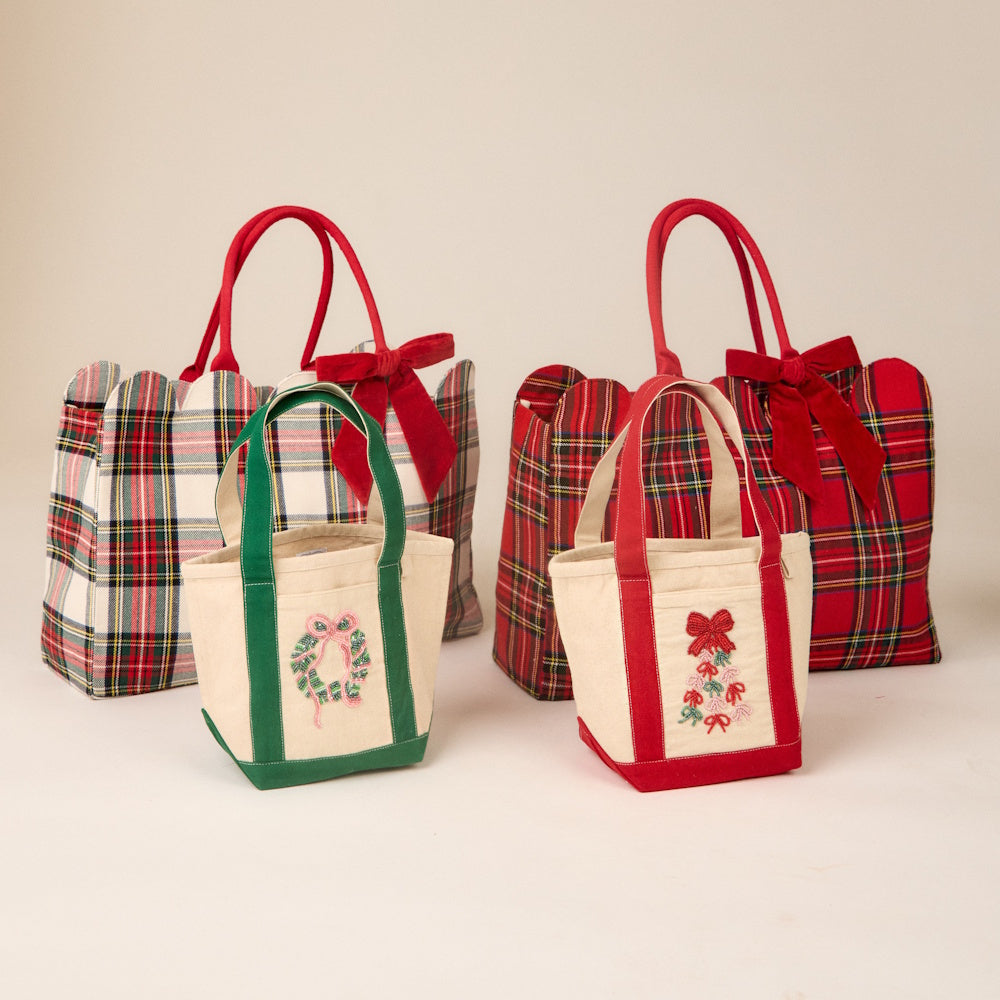 Holiday beaded mini canvas tote bags displayed in front of matching plaid bags with red bows.