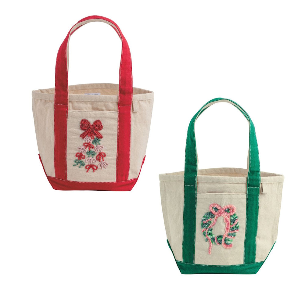 Two beige canvas mini tote bags with holiday beaded designs and red or green trim handles.