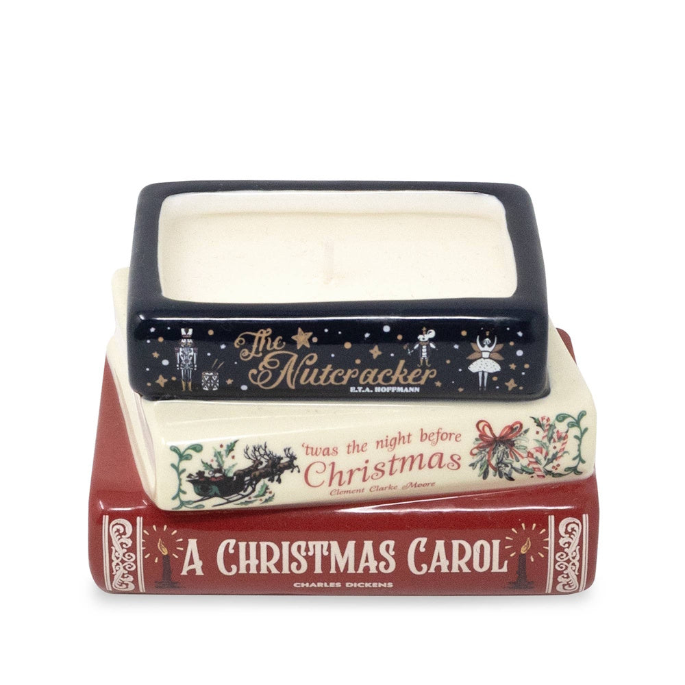 Candle in a container shaped like a stack of classic holiday books, including A Christmas Carol.