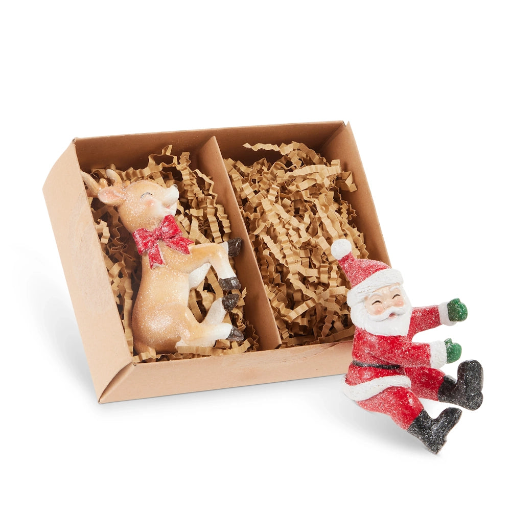 Reindeer and Santa candle huggers packaged in a divided brown box with crinkle paper.