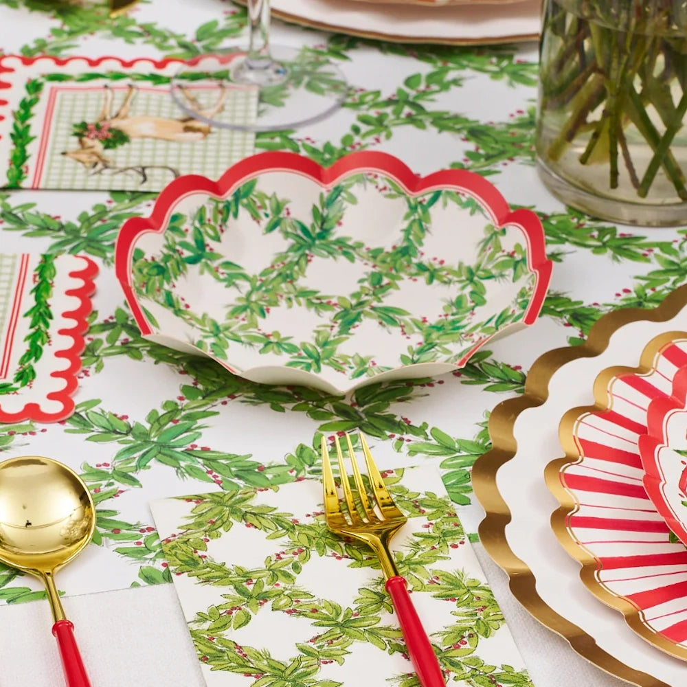 Front view of a holiday table setting with a red and green paper appetizer bowl in a holly lattice design.