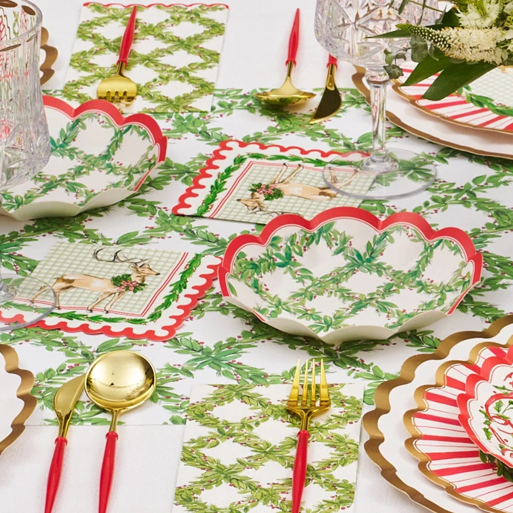 Front view of a holiday table setting featuring red and green paper appetizer bowls with a holly lattice.