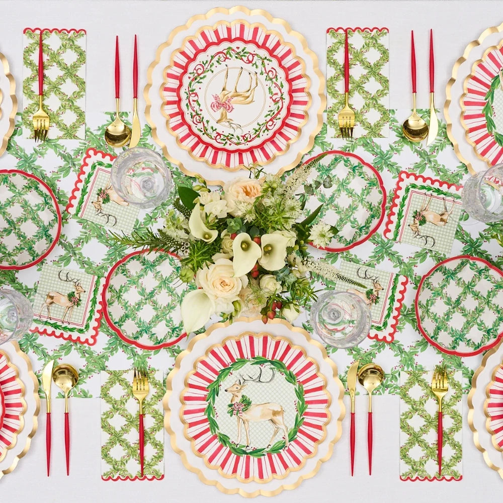 Overhead flat lay of white paper holiday cocktail napkins styled on a festive table.