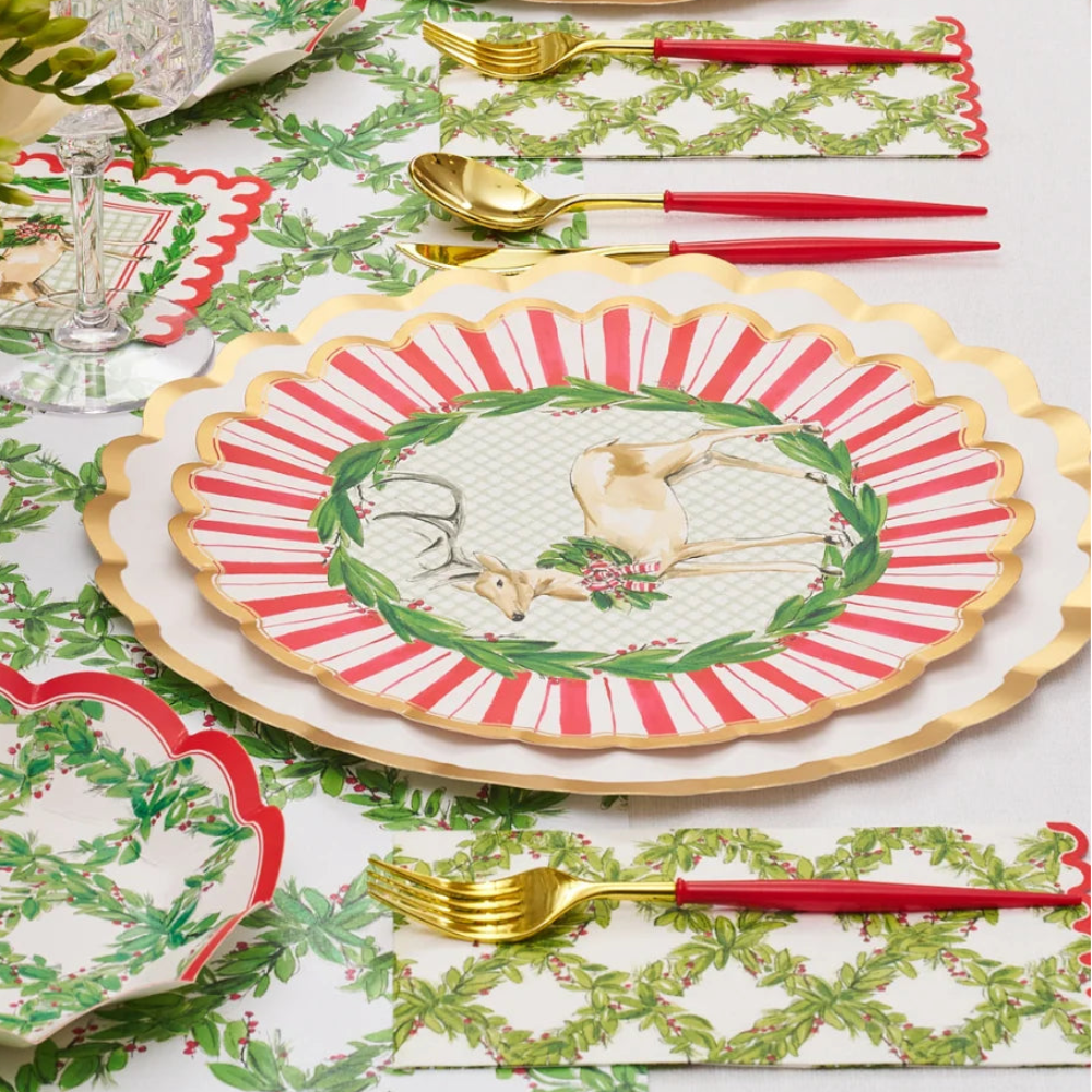 Angled view of a holiday table setting with red, white, and gold paper dinner plates and a deer design.