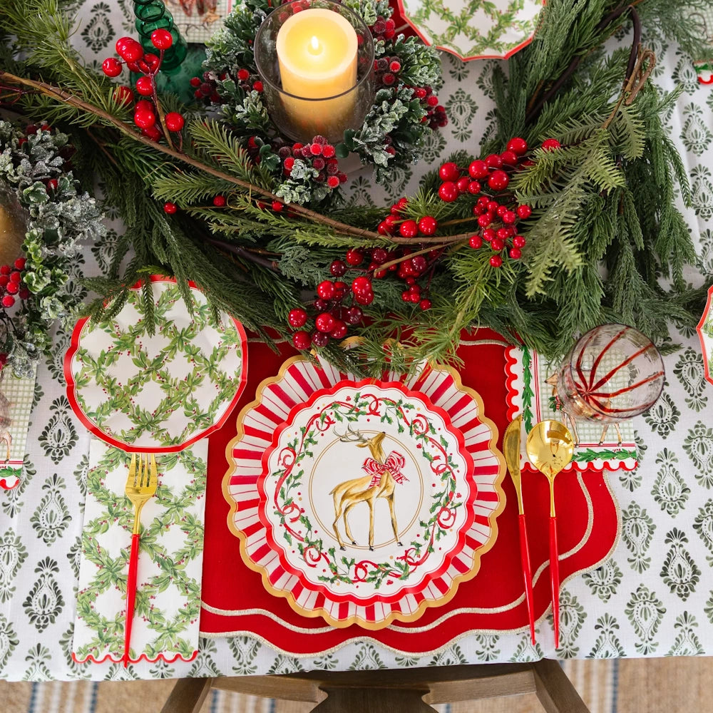 Overhead flat lay of a white paper Holly Berry guest towel on a festive holiday table setting.