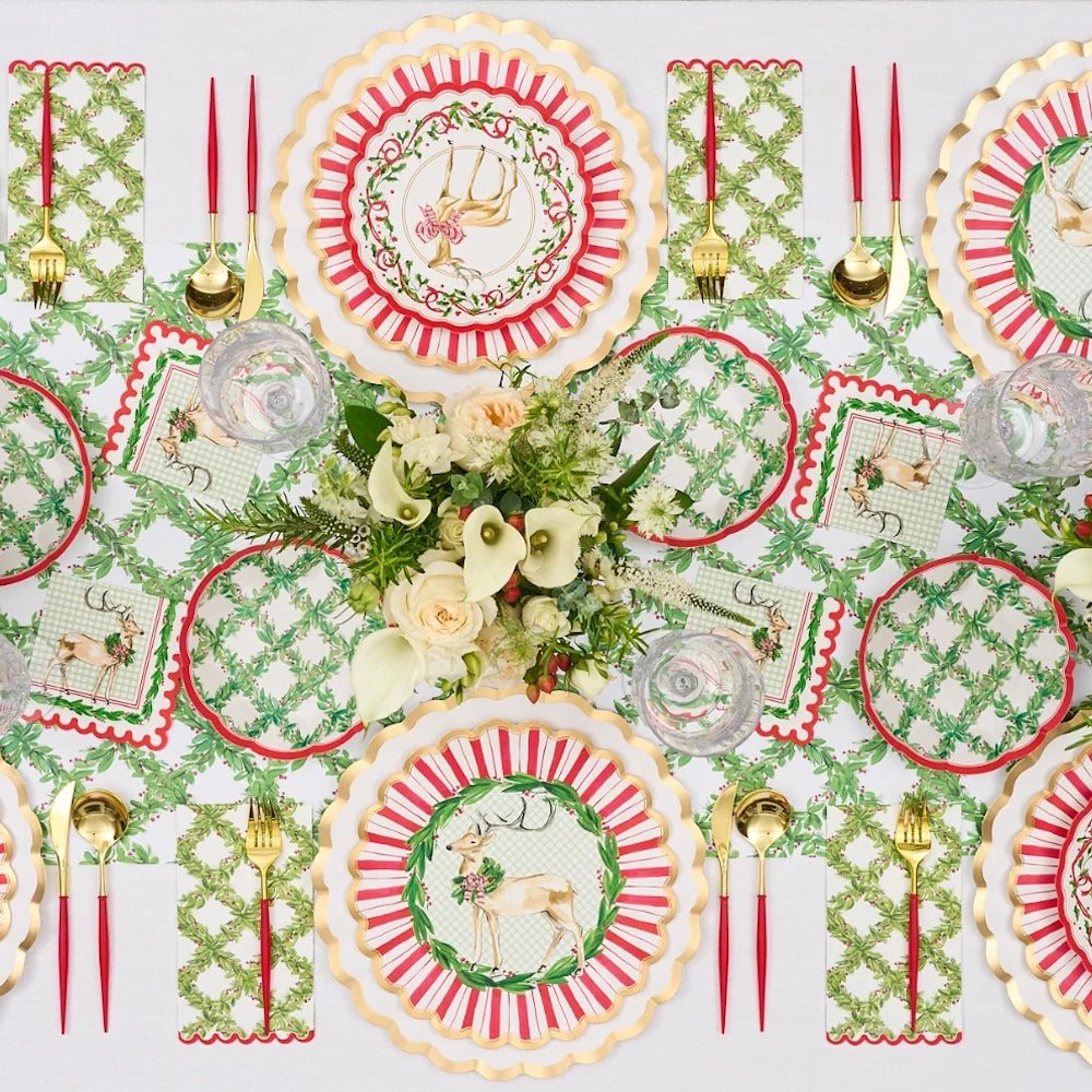 Flat lay view of red and white paper holiday salad plates styled in a full festive table arrangement.