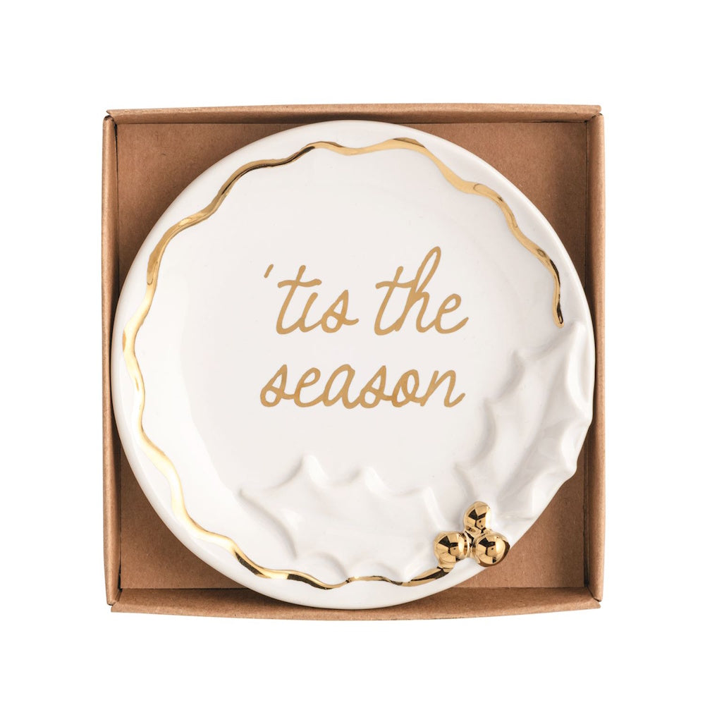 White ceramic trinket dish with gold rim, holly accent, and gold script reading "'tis the season".