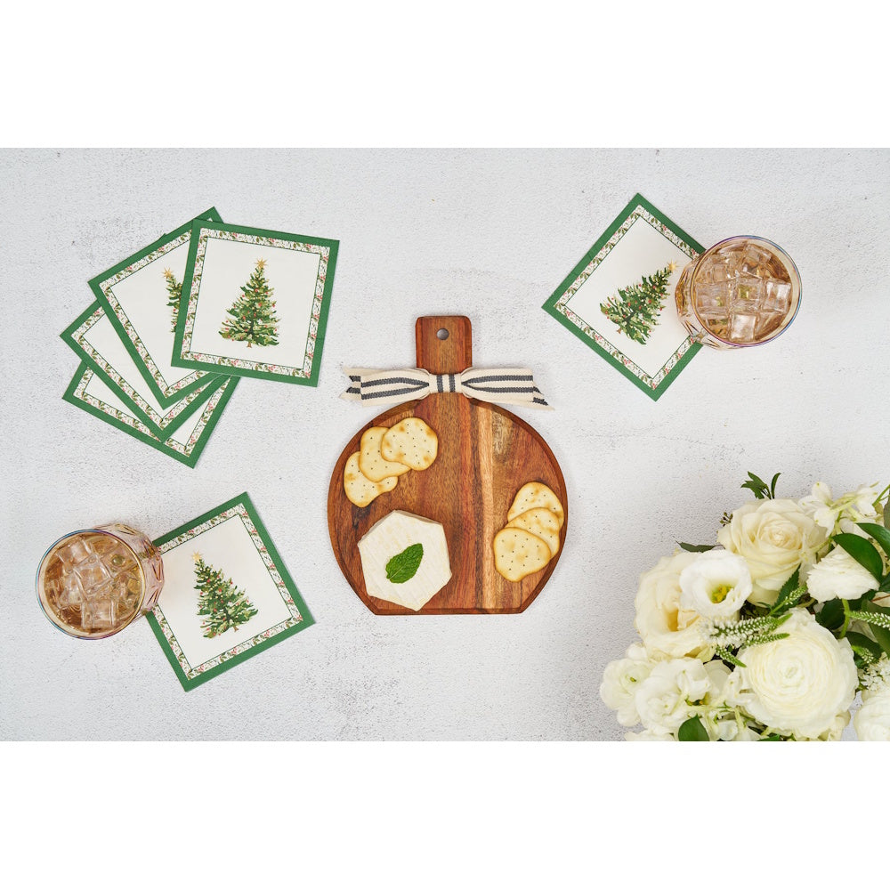 Flat lay view of a brown wooden holiday board gift kit styled with crackers, napkins, and white flowers.