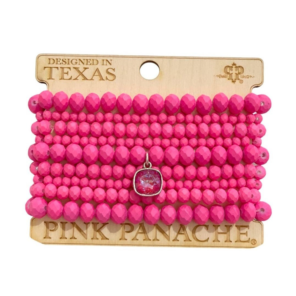 A stack of hot pink faceted beaded bracelets on a display card, featuring a central pink crystal charm.