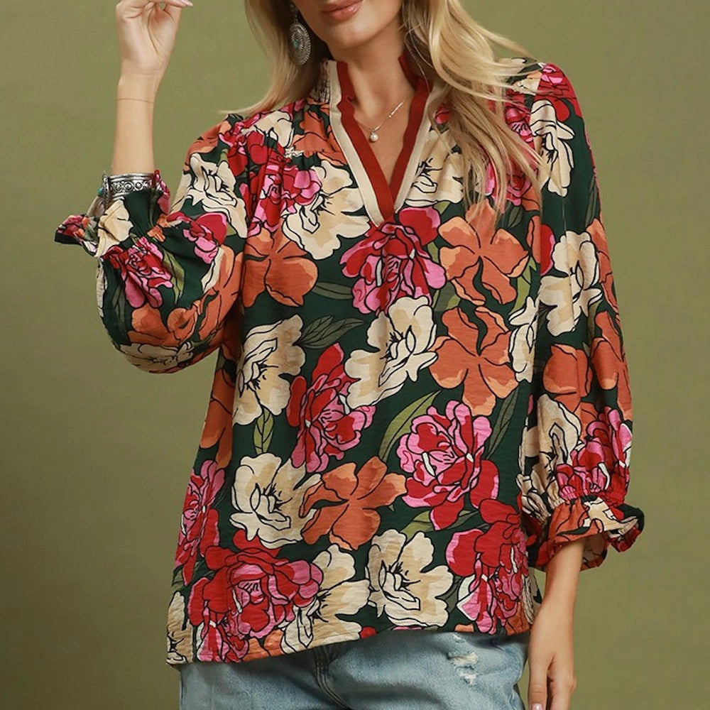 Front view of a hunter green floral print split-neck blouse with long sleeves and ruffled cuffs.