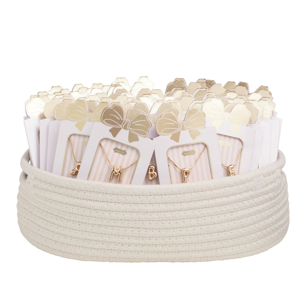 Cream woven basket filled with packaged gold initial pendant necklaces.