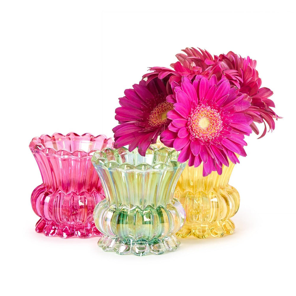 Three iridescent glass bud vases in pink, green, and yellow with pink flowers on a white background.