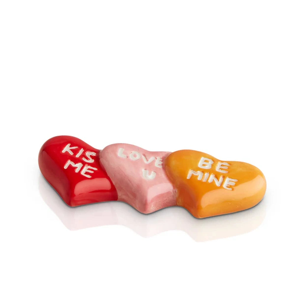 Red, pink, and orange conversation heart candies with "KISS ME," "LOVE U," and "BE MINE" text on a white background.