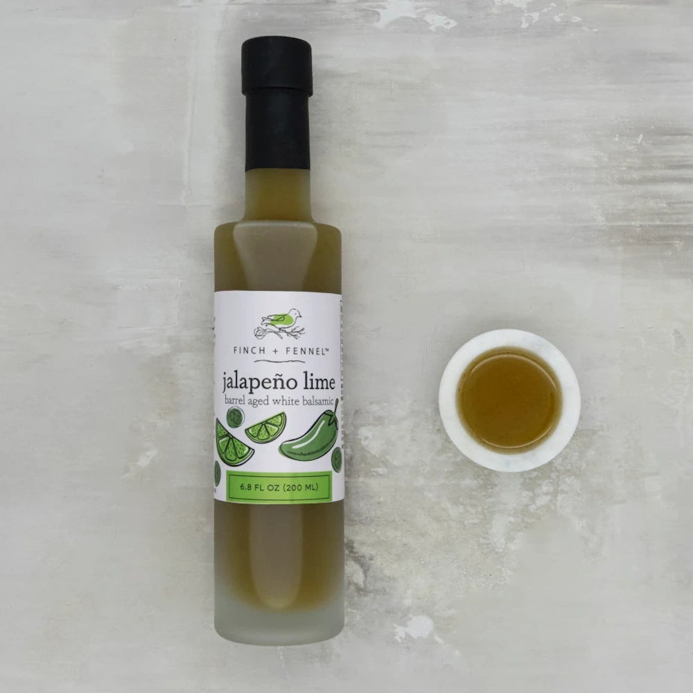 Finch + Fennel Jalapeño Lime Barrel Aged White Balsamic Vinegar bottle next to a small marble dipping bowl.
