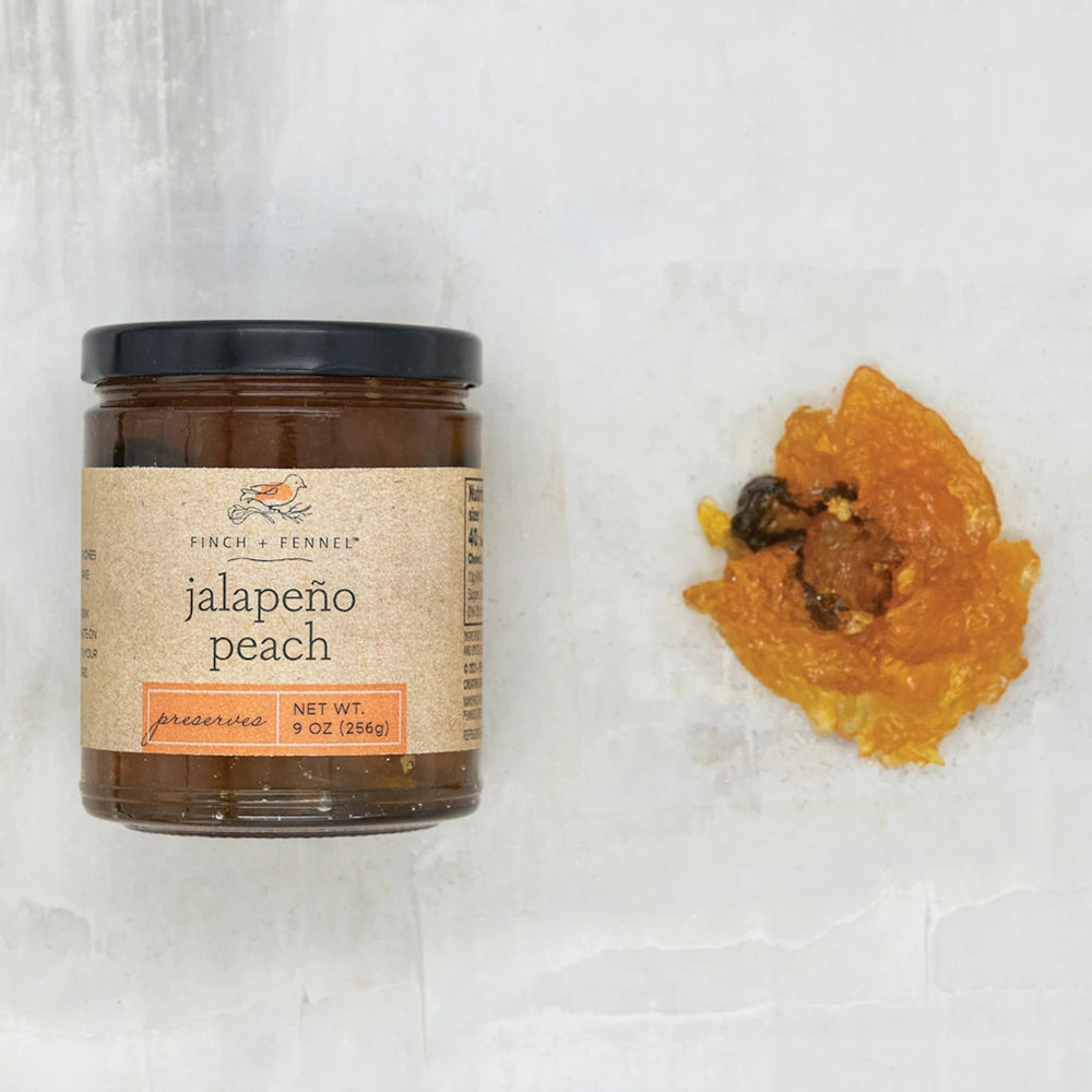 Jar of Finch + Fennel Jalapeño Peach Preserves next to a spoonful of amber peach preserves.